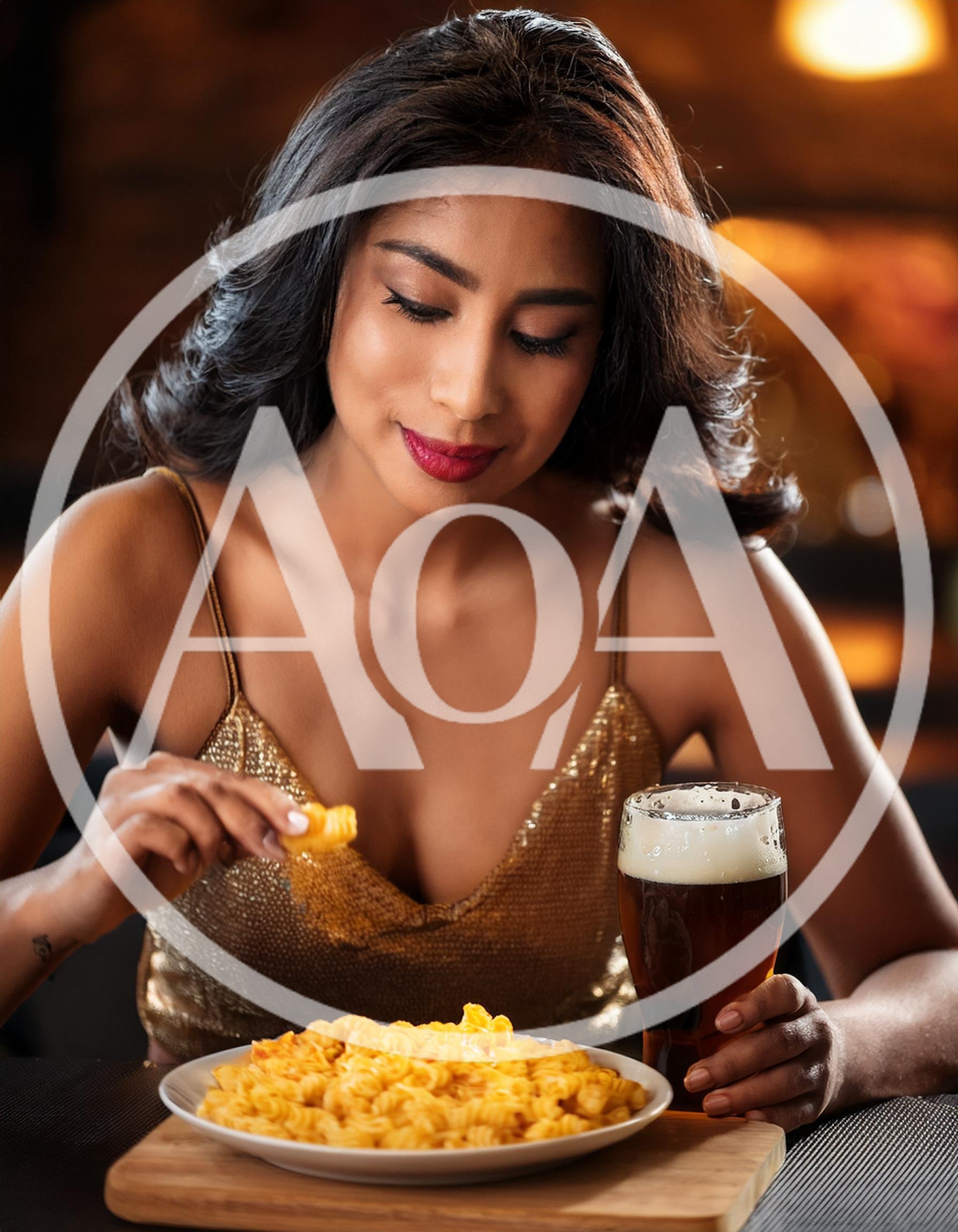 Young Woman Eating Pasta and Drinking Beer at Restaurant