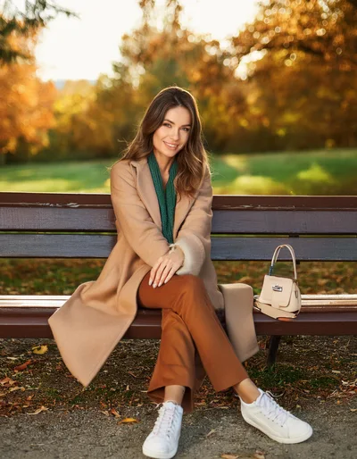 Young Woman Sitting On A Park Bench In Autumn
