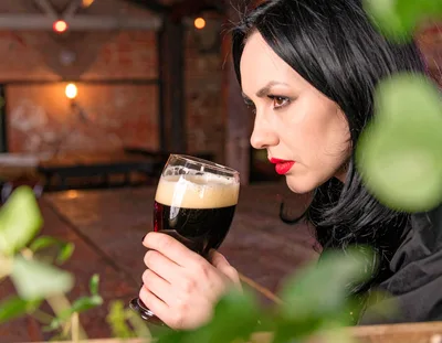 Woman Smelling A Glass Of Dark Craft Beer