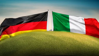 German and Italian Flags Waving Over Green Hill