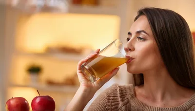 Young Woman Drinking Fresh Apple Juice At Home