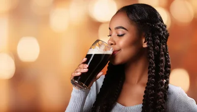 Young Woman Enjoying A Glass Of Dark Stout Beer