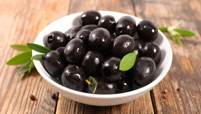 Bowl Of Pitted Black Olives On Wooden Table