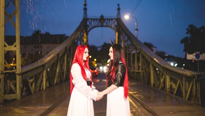 Two Gothic Women Holding Hands on a Rainy Bridge