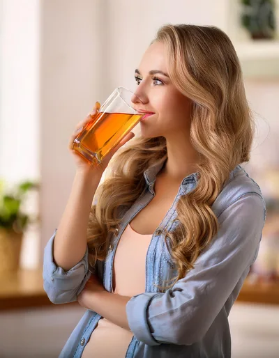 Young Woman Drinking Apple Juice In A Bright Kitchen