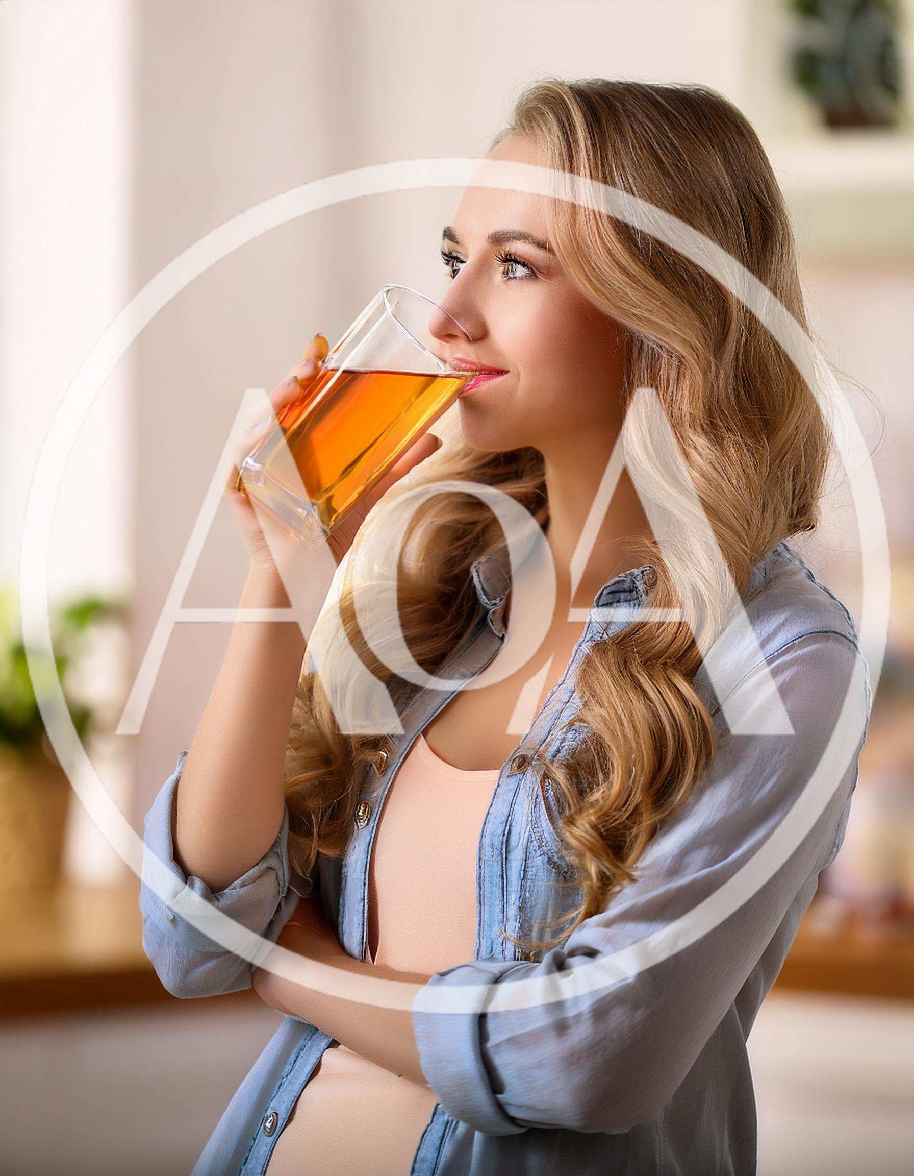 Young Woman Drinking Apple Juice In A Bright Kitchen