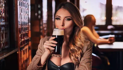 Beautiful Woman Drinking Dark Beer In A Pub