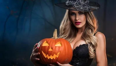 Beautiful Woman Dressed As A Witch Holding A Pumpkin