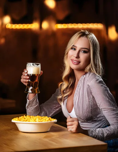 Young Woman Enjoying Beer and Snacks at a Bar