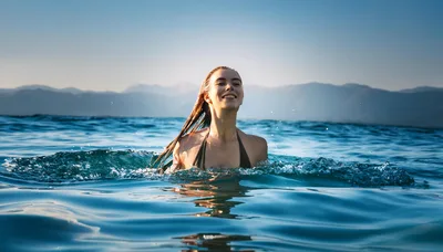 Young Woman Swimming In A Calm Mountain Lake