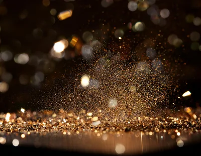 Golden Glitter Particles Exploding Against Dark Background