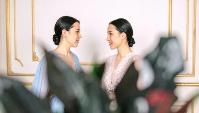 Two Elegant Women In Evening Gowns Looking At Each Other