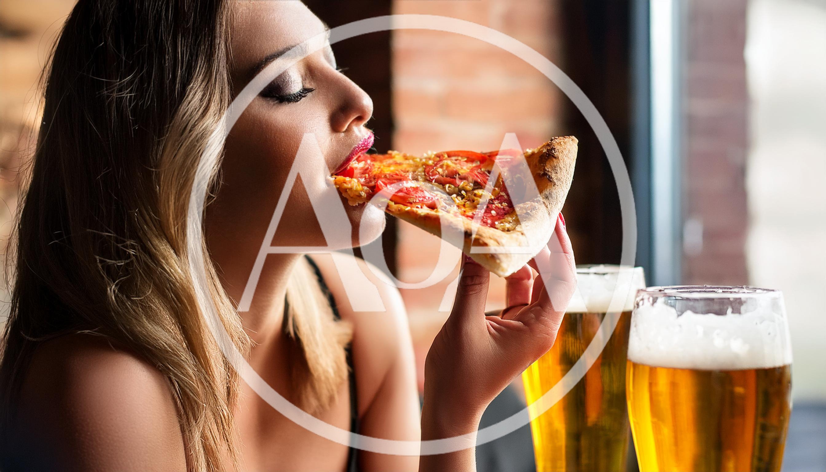 Young Woman Eating Pizza Slice With Beer