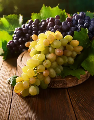 Fresh Green and Purple Grapes on Wooden Board