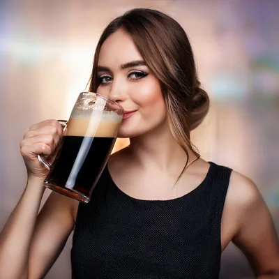 Young Woman Drinking Dark Beer From A Glass Mug