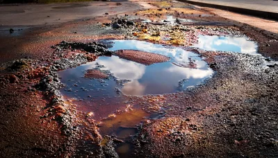 Large Pothole Filled With Rainwater On Damaged Asphalt Road