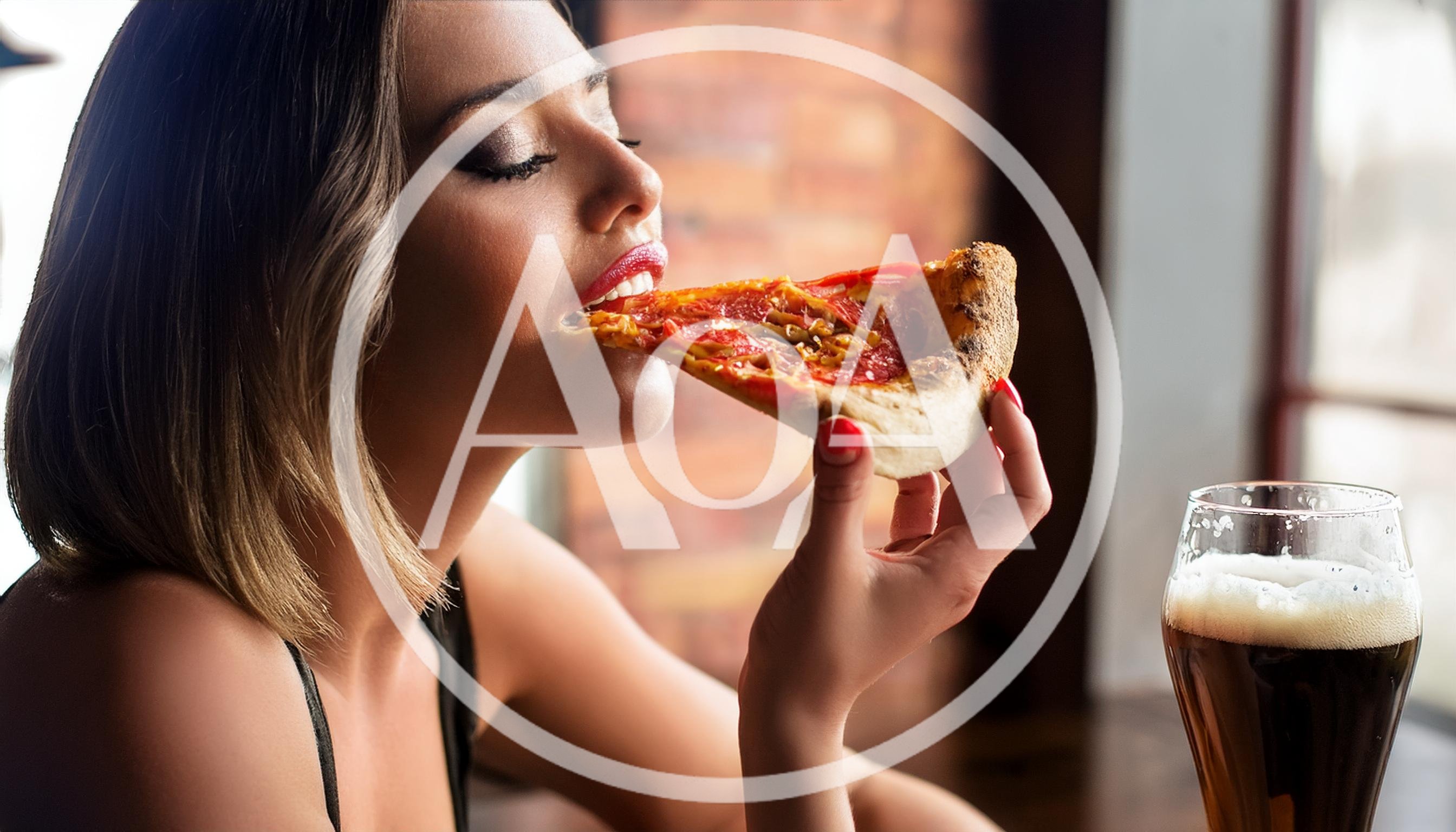 Young Woman Eating Pizza Slice In A Restaurant