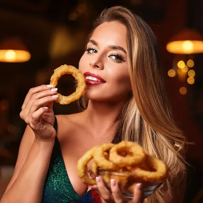 Beautiful Woman Eating Crispy Onion Rings In Restaurant