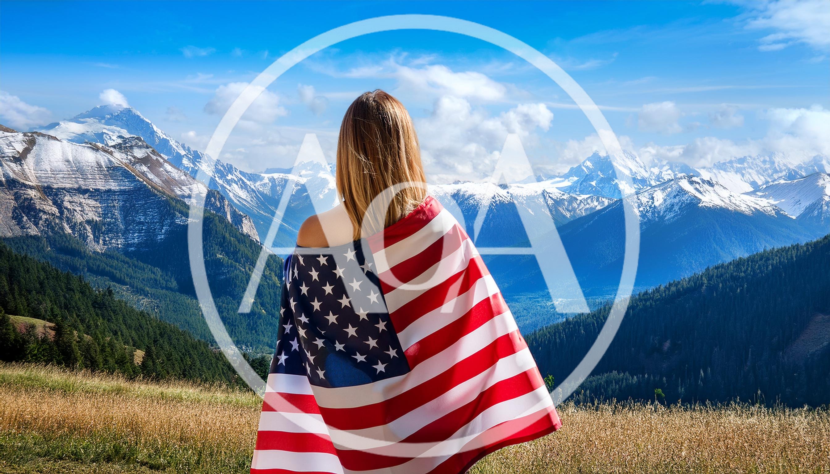 Woman Standing With American Flag Overlooking Mountain Range