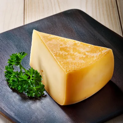Wedge of Aged Cheese on Dark Wooden Board