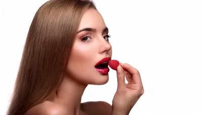 Beautiful Woman Holding A Fresh Raspberry To Her Lips