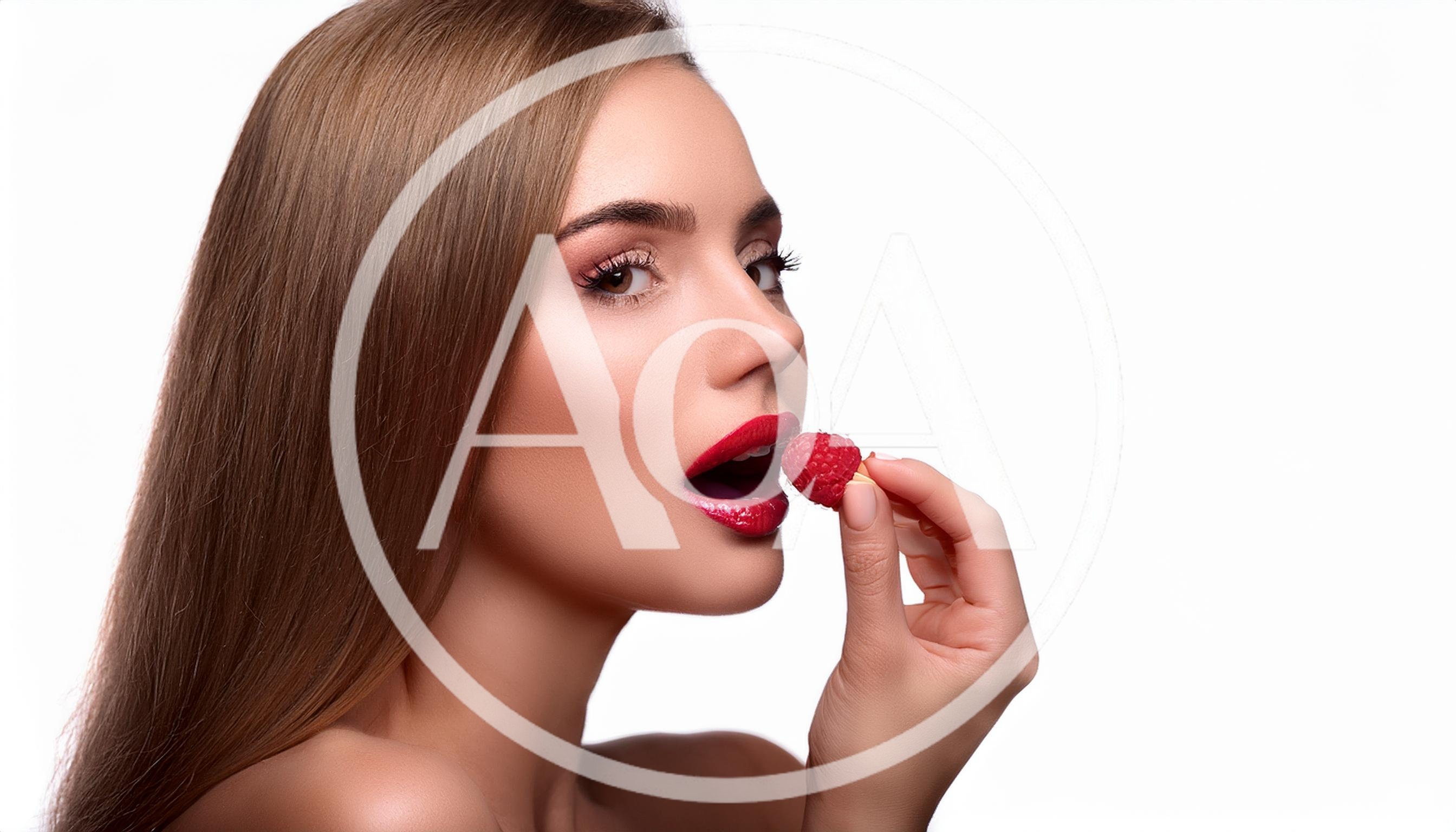 Beautiful Woman Holding A Fresh Raspberry To Her Lips