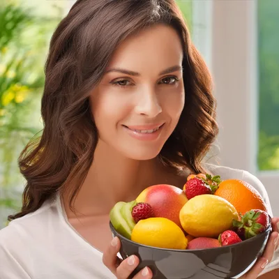 Smiling Woman Holding A Bowl Of Fresh Fruit