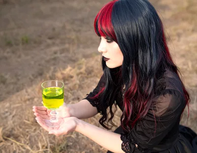 Goth Woman Holding A Glass Of Glowing Green Potion