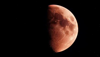 Red Half Moon Against A Dark Starry Sky