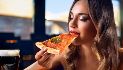 Young Woman Eating A Slice Of Pizza
