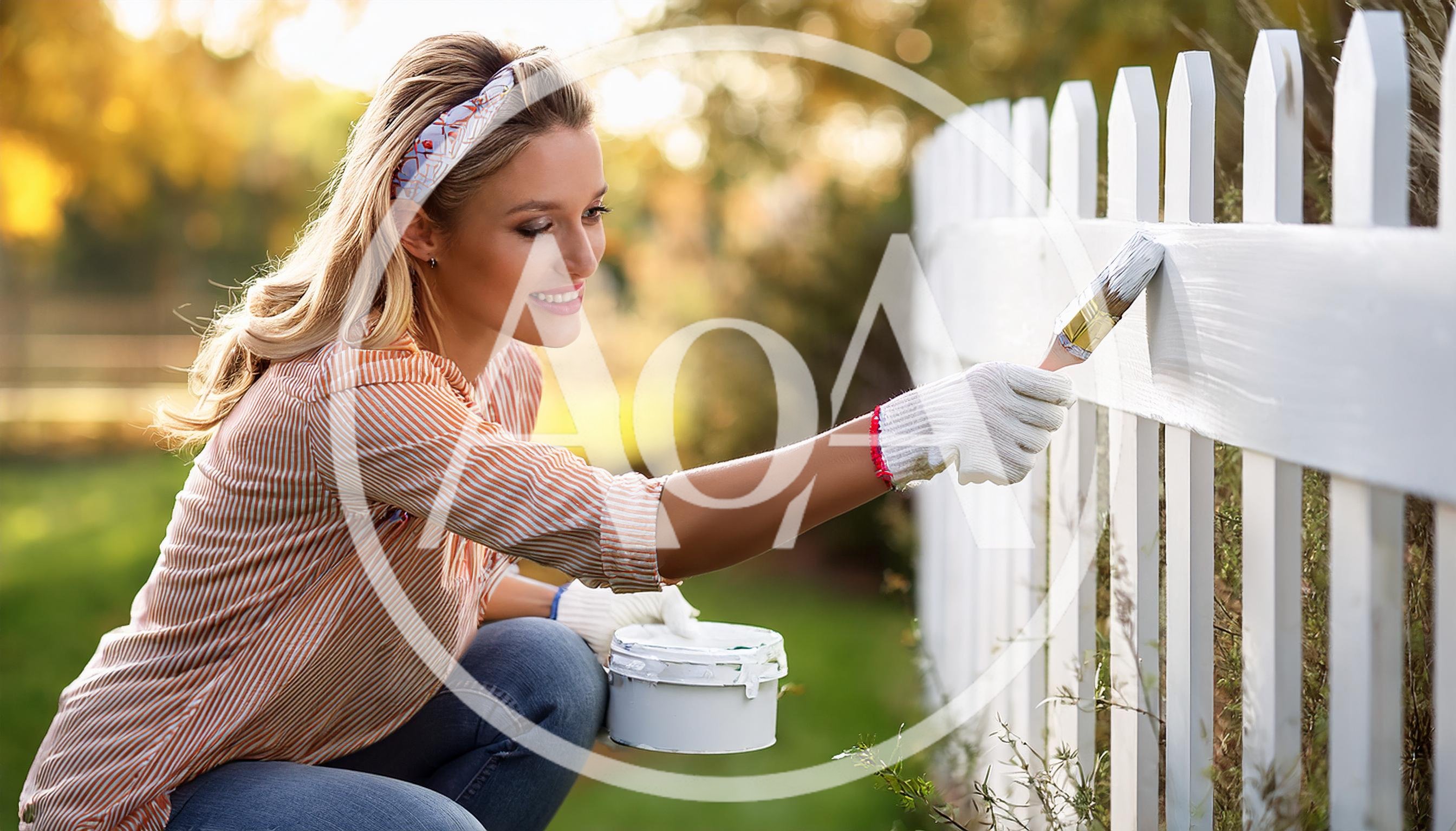 Young Woman Painting A White Picket Fence