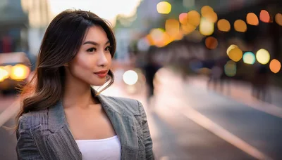 Young Asian Woman Standing On City Street At Dusk