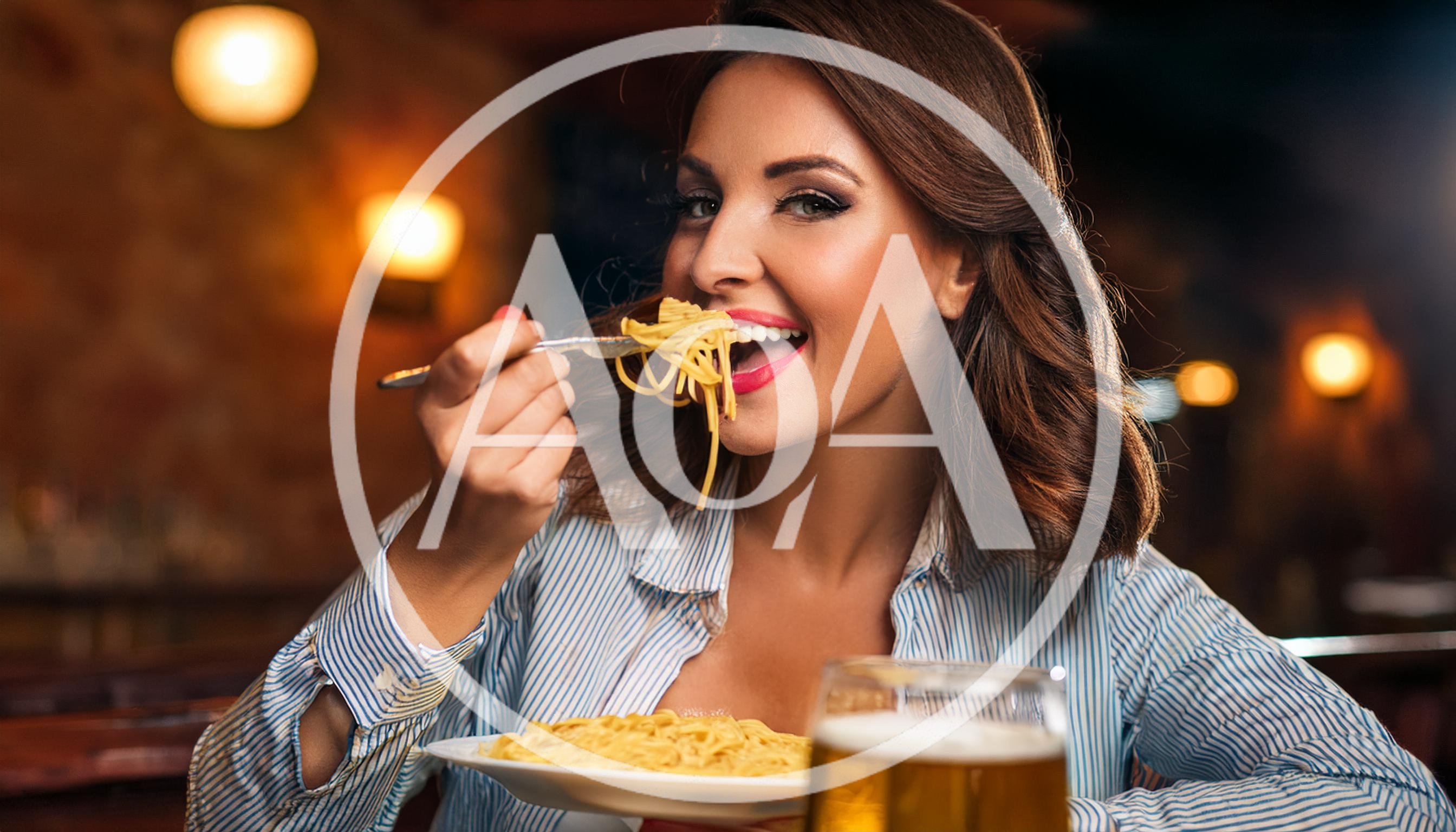 Woman Eating Spaghetti and Drinking Beer in Restaurant
