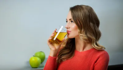Young Woman Drinking Apple Juice With Green Apples