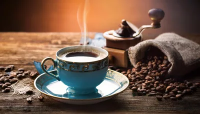 Steaming Cup Of Coffee With Beans And Grinder