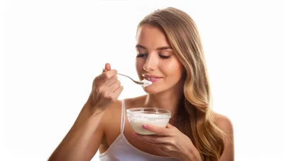 Young Woman Eating Yogurt From A Glass Bowl