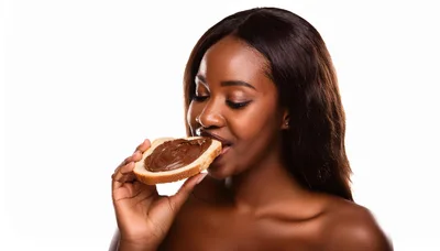 Young Black Woman Eating Chocolate Spread On Bread