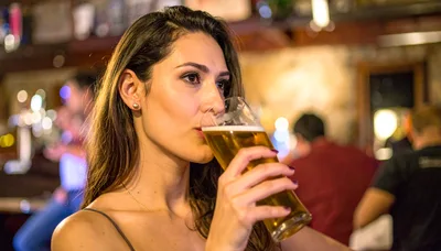 Young Woman Drinking Beer In A Pub