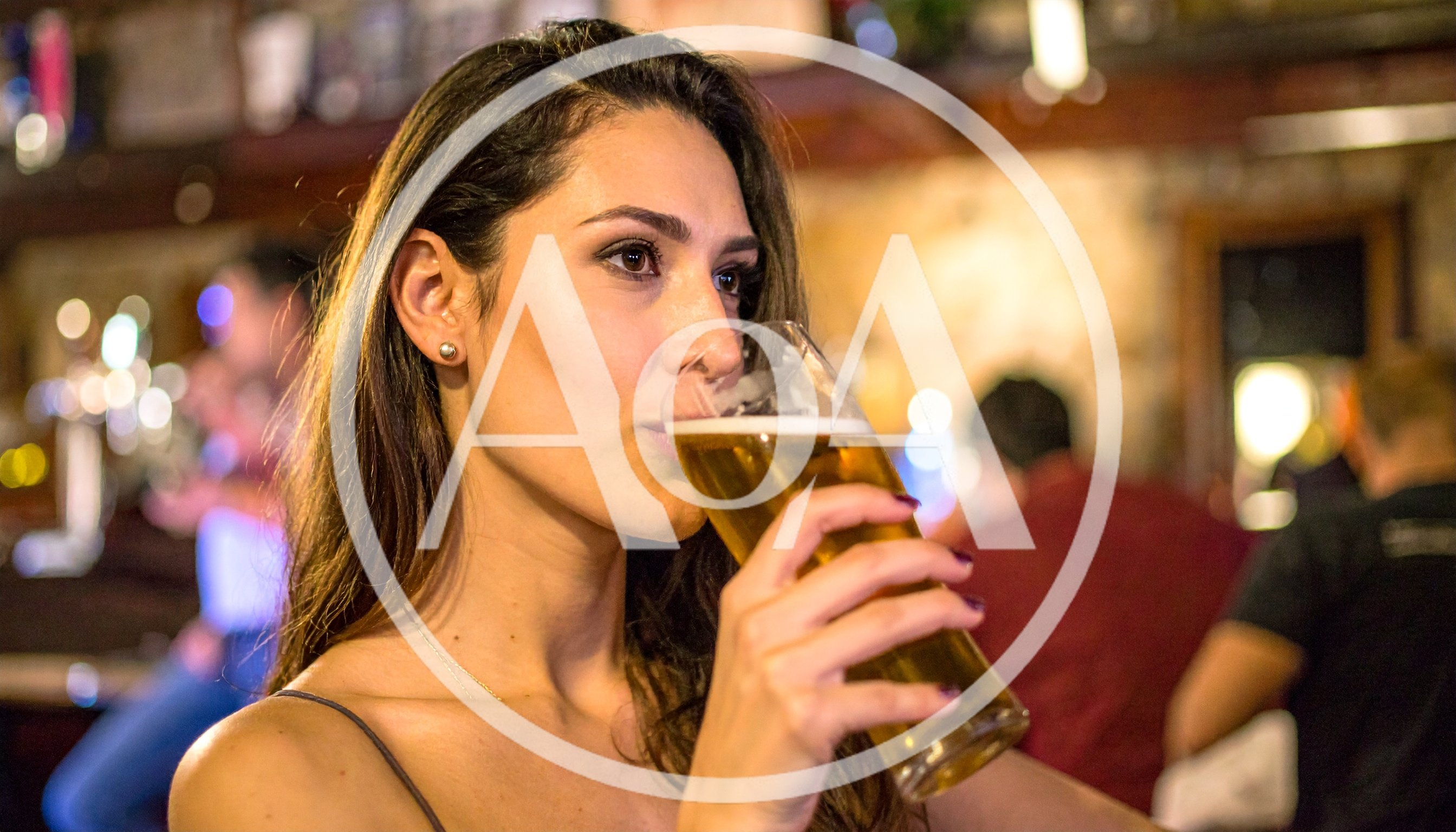 Young Woman Drinking Beer In A Pub