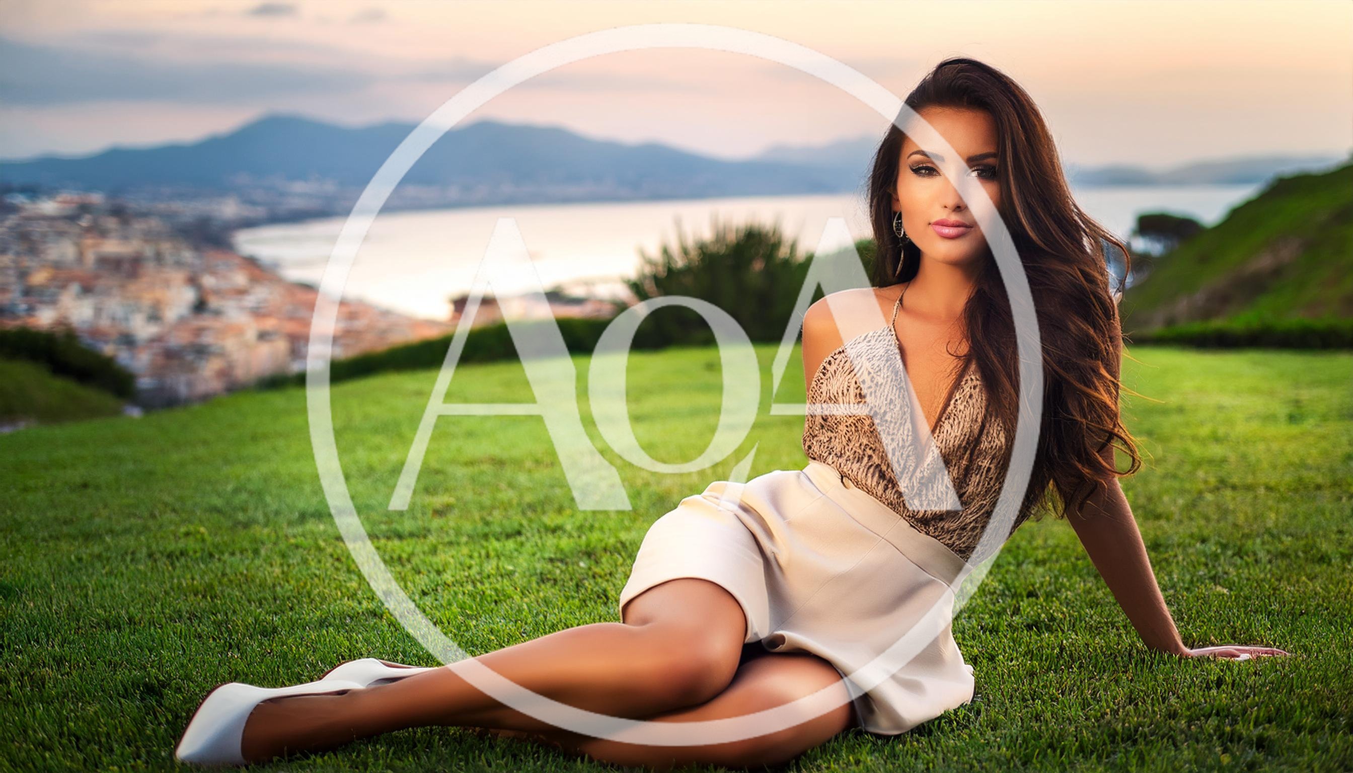 Beautiful Woman Sitting On Grass Overlooking Coastal City