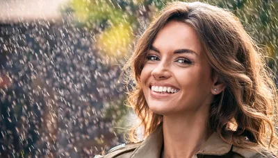 Smiling Woman Standing Under Falling Rain Outdoors