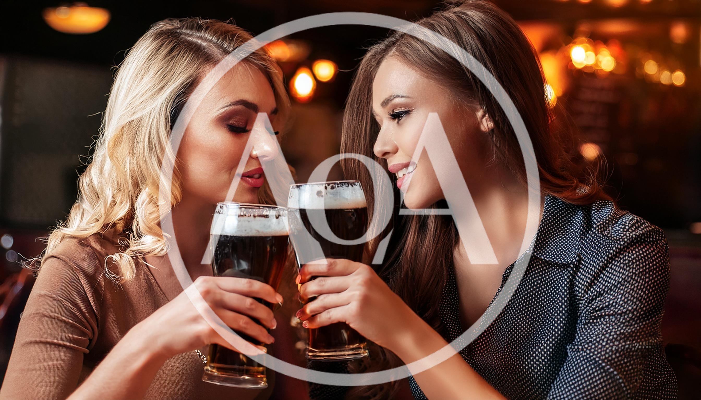 Two Young Women Toasting With Dark Beer Glasses