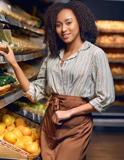 Smiling Female Grocery Store Clerk Arranging Fresh Produce