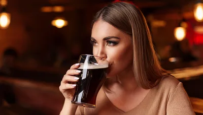 Young Woman Drinking Dark Beer in a Pub