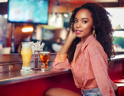 Young Woman Sitting At A Bar With Drinks