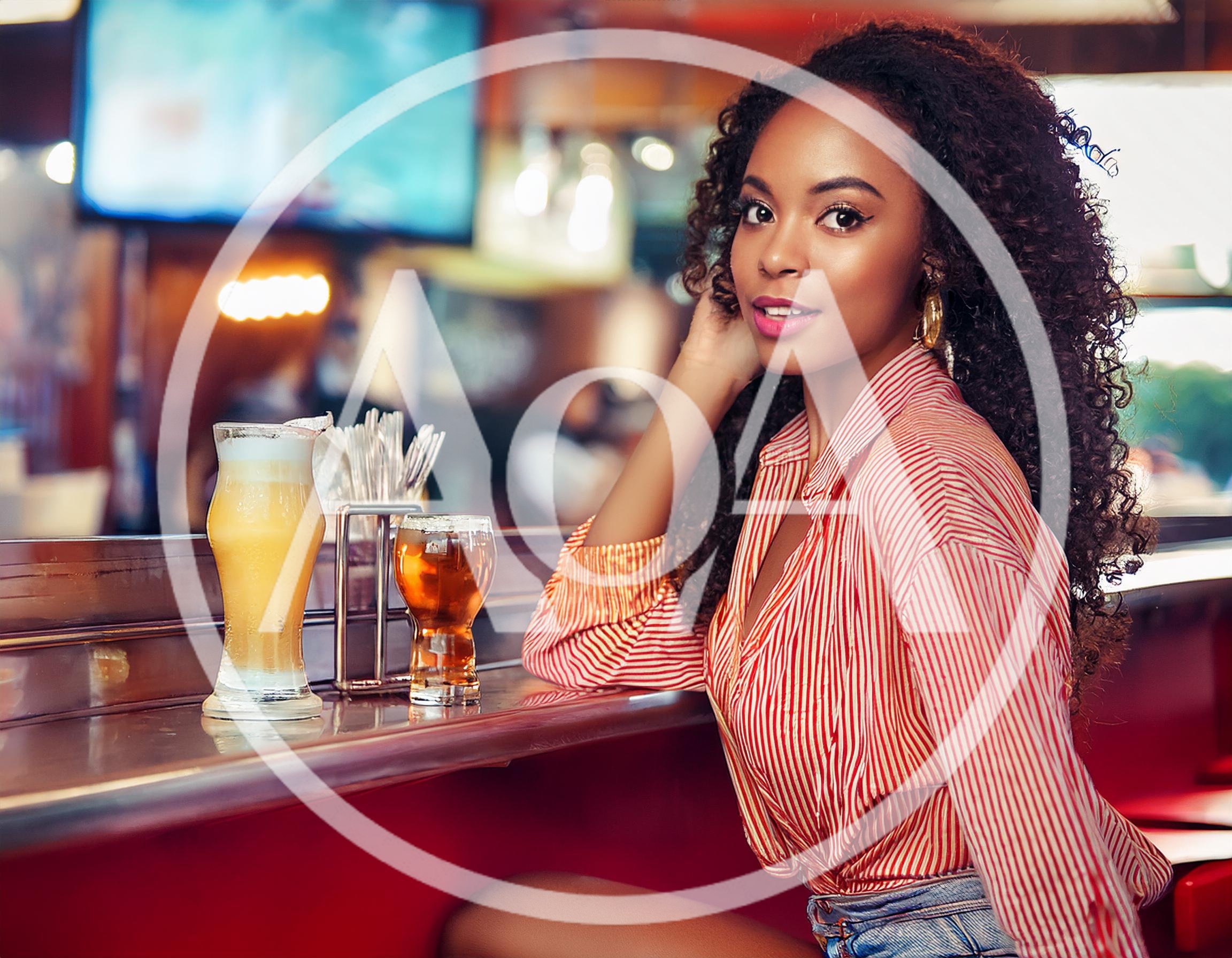 Young Woman Sitting At A Bar With Drinks