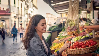 Young Woman Shopping For Fresh Tomatoes At Outdoor Market