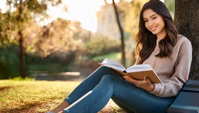 Young Woman Reading A Book Under A Tree