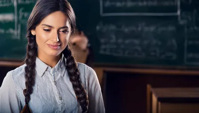 Young Female Teacher Standing In A Classroom