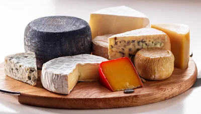 Assorted Gourmet Cheeses Arranged On A Wooden Board